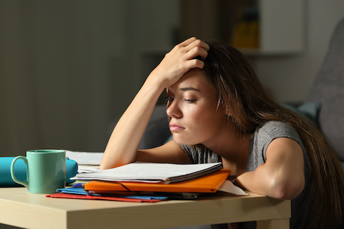 A student working on her homework, but is looking stressed out.