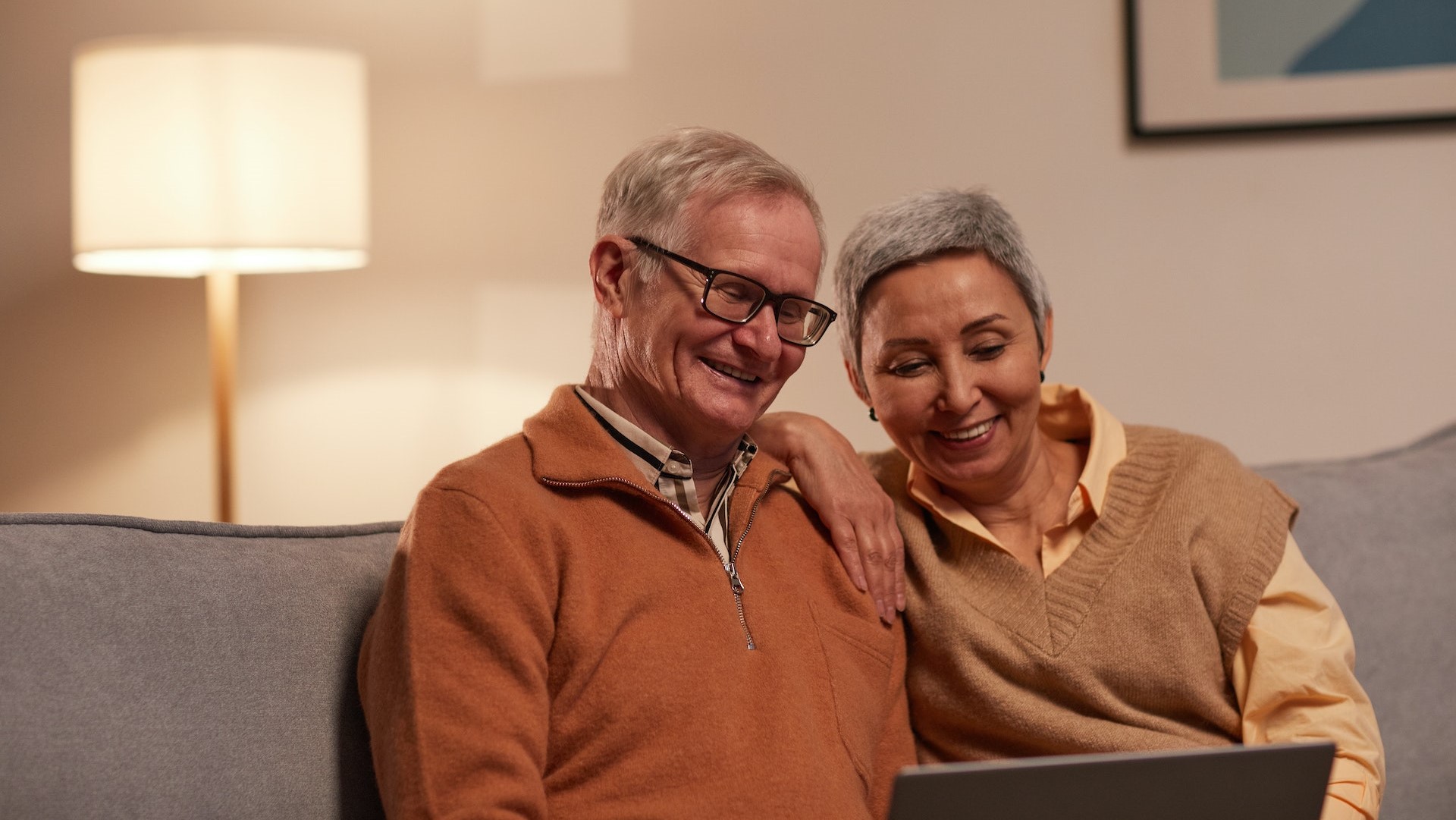 Elderly couple sitting on couch with computer