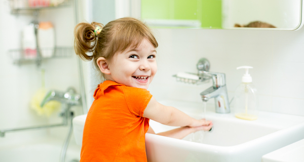 A young student washing her hands, practicing good hygiene.