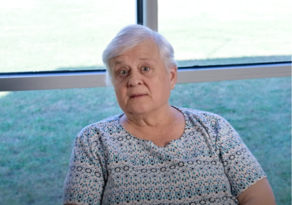 Barbara Rasmussen Adena Health cardiology patient Barbara Rasmussen seated indoors near a window, speaking during a video testimonial.
